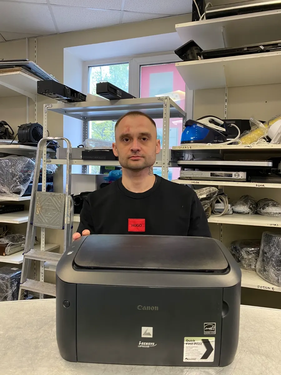 Мастер держит принтер Canon i-SENSYS после ремонта